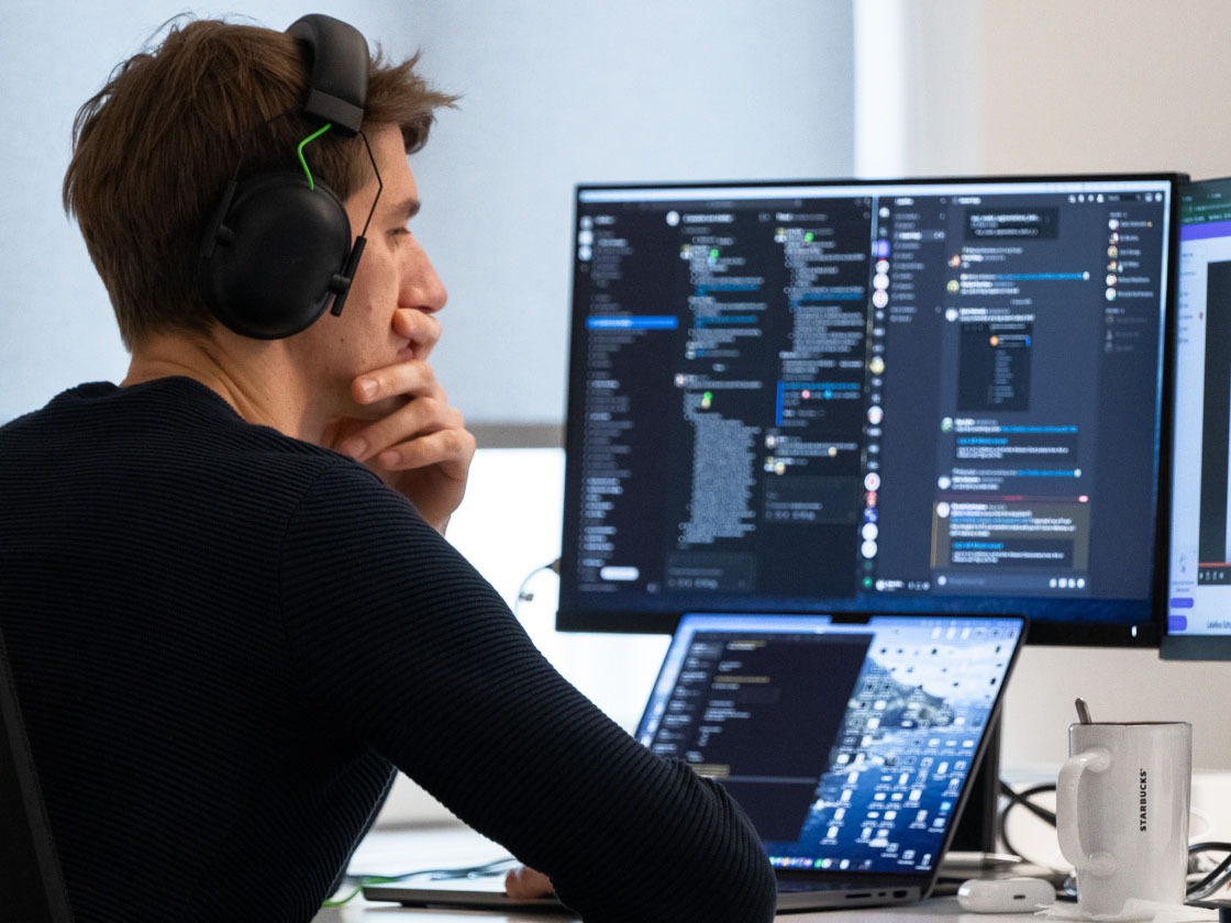 Ingeniero de accesibilidad que tiene auriculares y que mira los monitores.