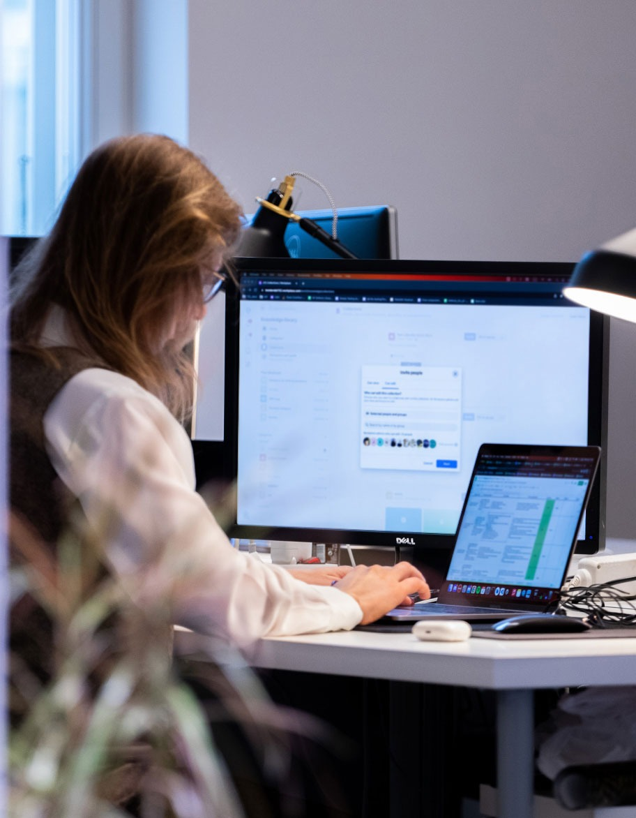 En expert på digital tillgänglighet sitter vid sitt skrivbord och arbetar med en dator.