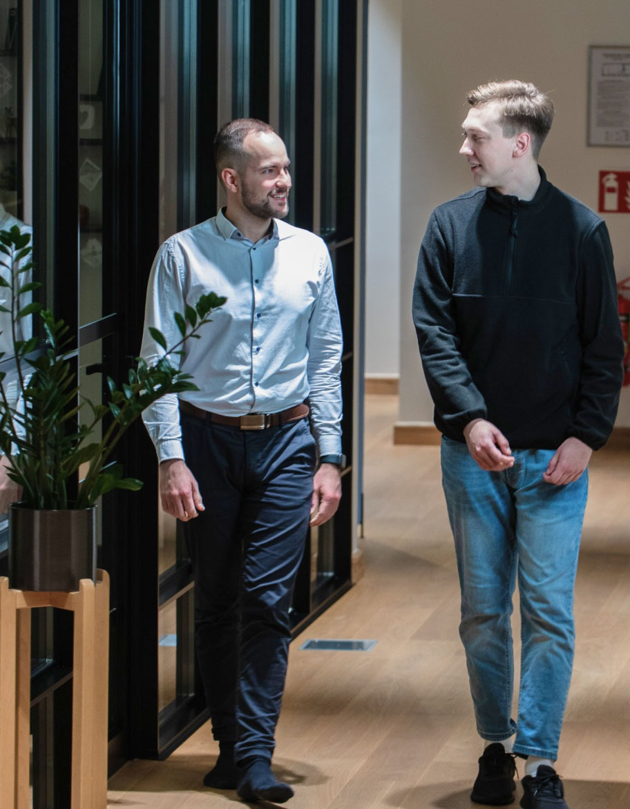 Two engineers chatting and walking down the hallway.