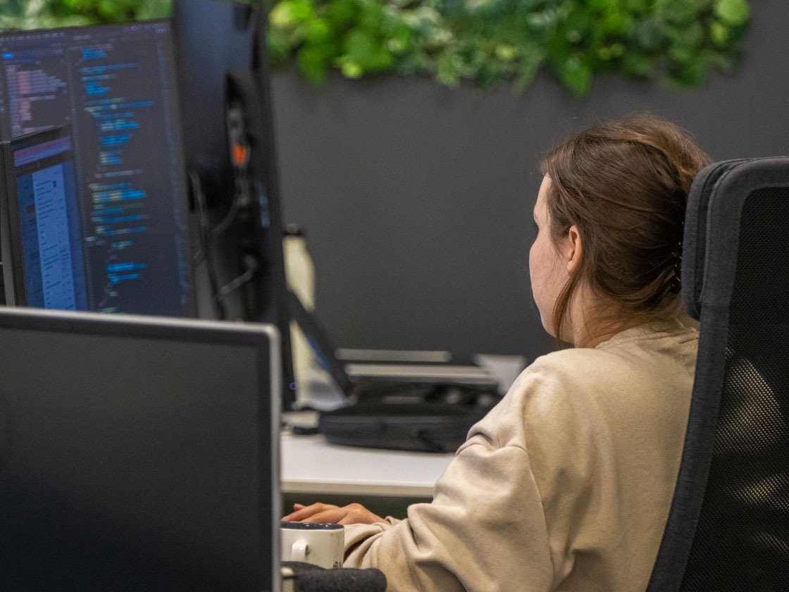 Ingeniera de accesibilidad que mira el monitor para realizar pruebas de accesibilidad mientras está sentada en su escritorio.