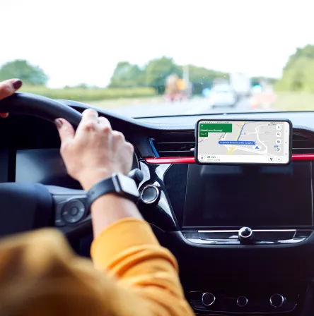 A person driving a car and using navigation on a mobile device.