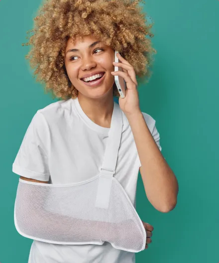 A woman with her arm in a cast talking on a mobile phone.