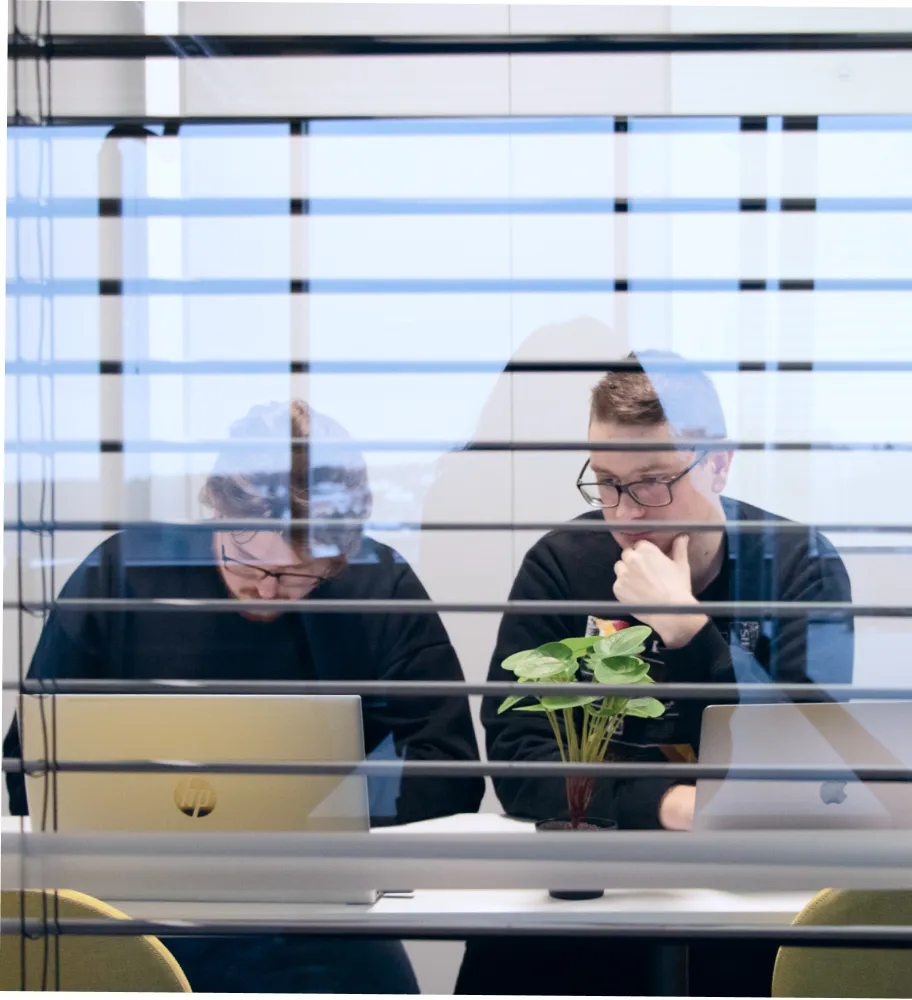 Kaksi QA-insinööriä istuu työpöydän ääressä ja keskustelee projektin päivityksistä.
