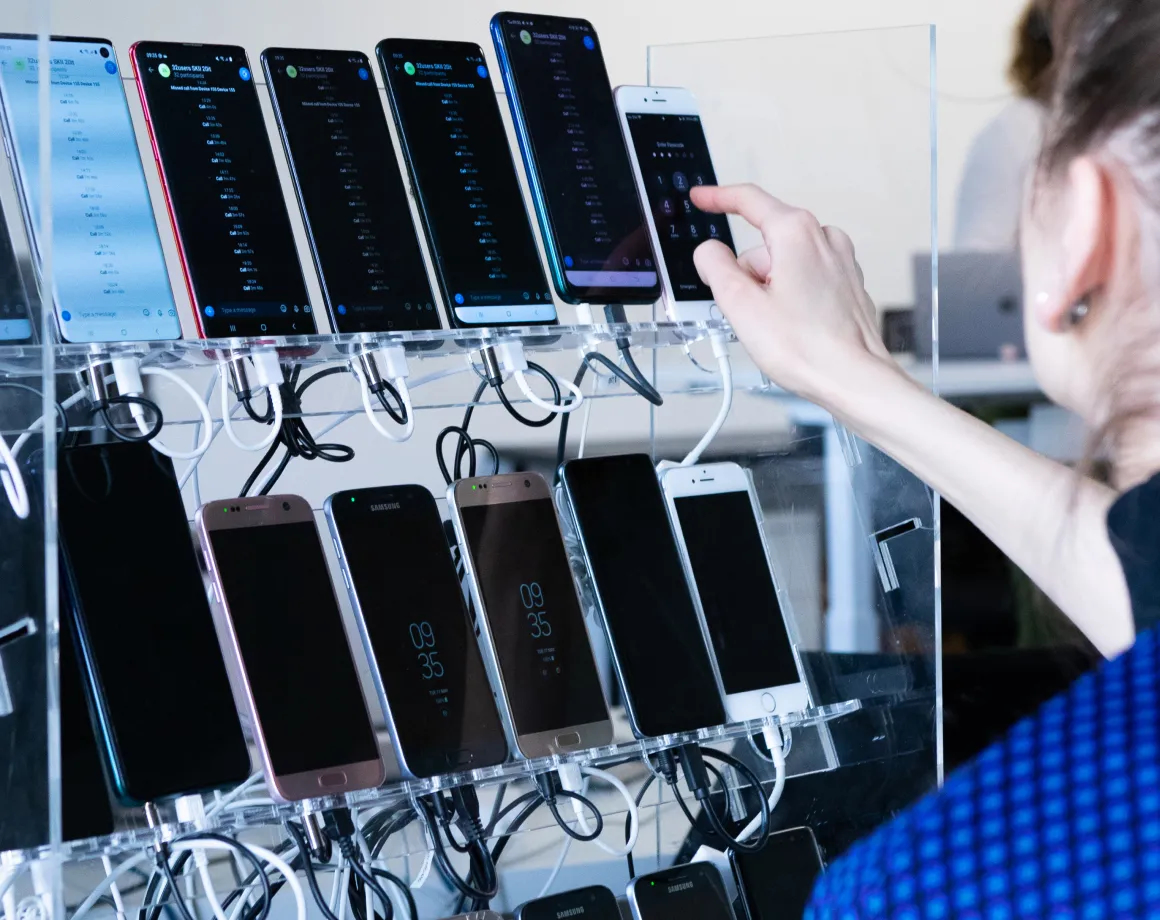 A person setting up a rack of devices dedicated to test automation.
